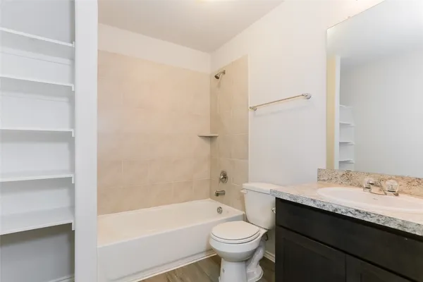 a bathroom with a granite countertop sink toilet mirror and bathtub