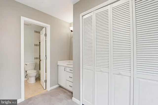 a bathroom with a granite countertop sink vanity mirror and toilet