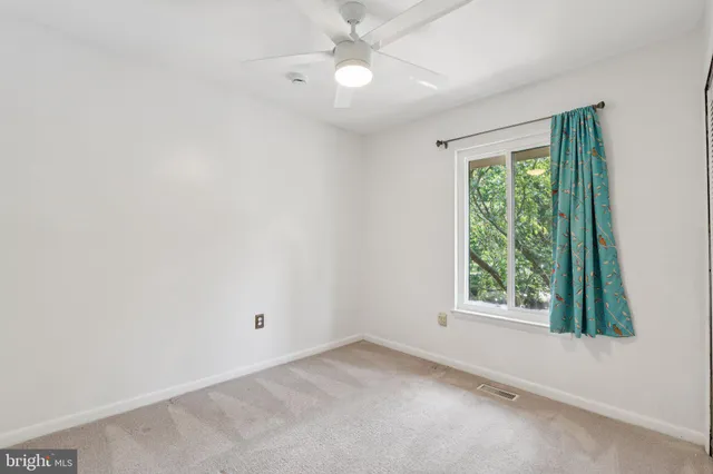 an empty room with a ceiling fan and a window