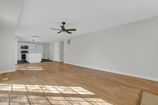 a view of empty room with wooden floor and window