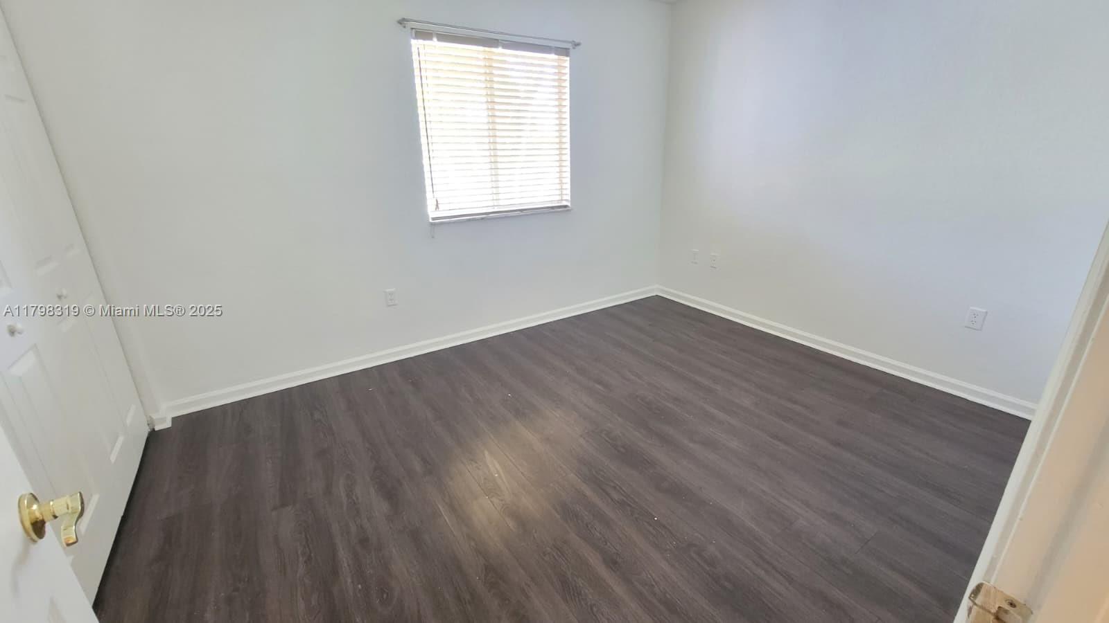 8353 Southwest 26 Th Street, Unit 104 Miramar, FL 33025 - Photo 10 of 14 an empty room with wooden floor and windows