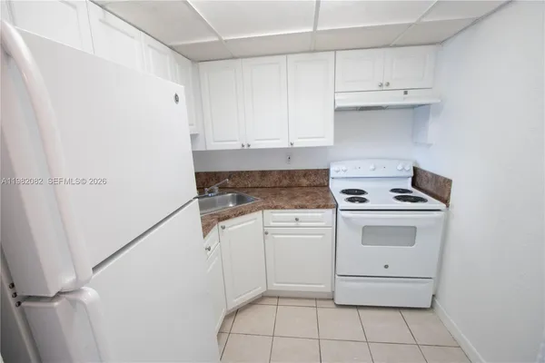 a kitchen with white cabinets washer and dryer