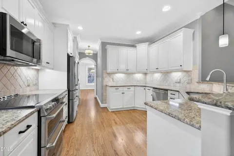 a kitchen with kitchen island granite countertop a stove top oven a sink cabinets and wooden floor