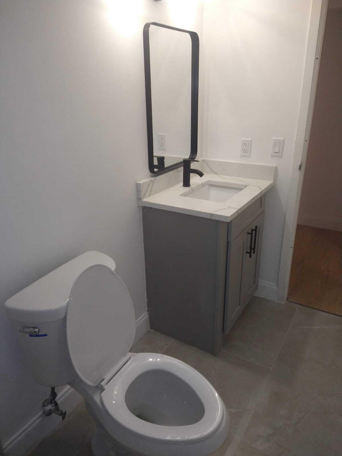 8321 Sands Point Boulevard, Unit D109 Tamarac, FL 33321 - Photo 14 of 16 a bathroom with a toilet sink and mirror