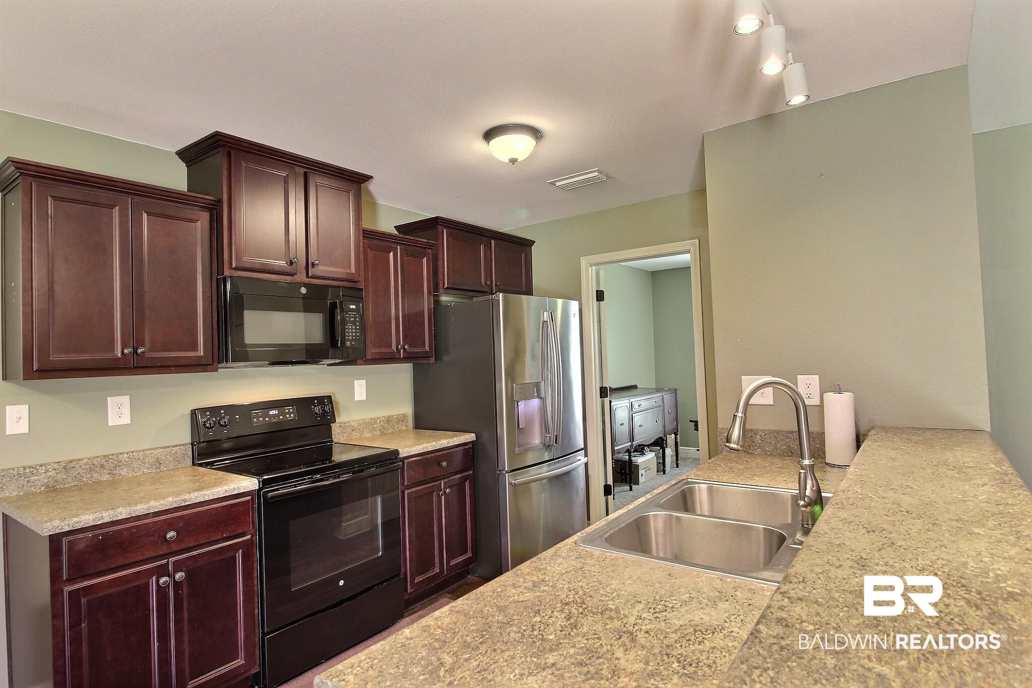 15577 Talus Court Foley, AL 36535 - Photo 8 of 28 Kitchen with black appliances, light stone countertops, and dark brown cabinets