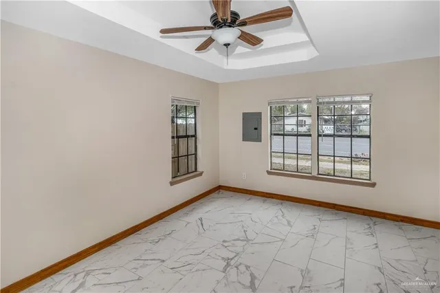 an empty room with chandelier fan and windows