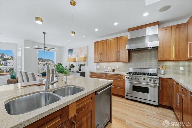 a kitchen with kitchen island stainless steel appliances a sink stove and cabinets