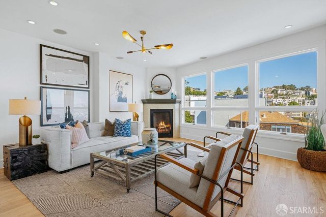 a living room with furniture a fireplace and a floor to ceiling window