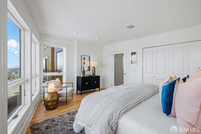 a spacious bedroom with a bed a couch and large windows