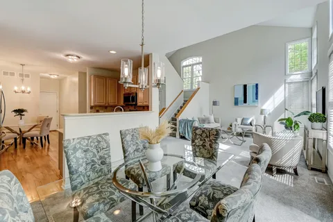 a living room with furniture kitchen view and a chandelier