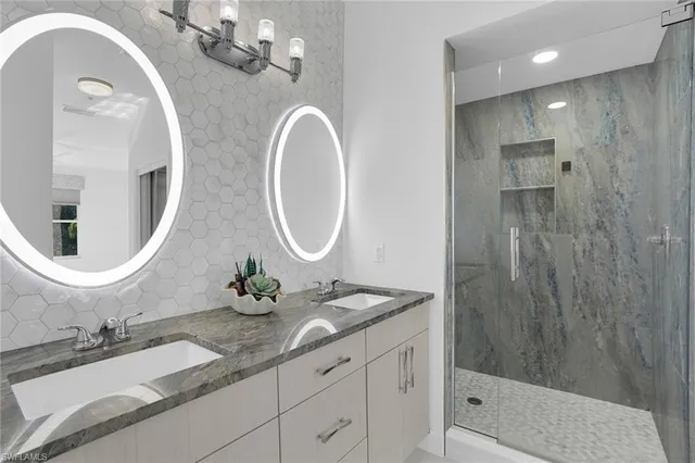 a bathroom with a granite countertop sink a mirror and shower