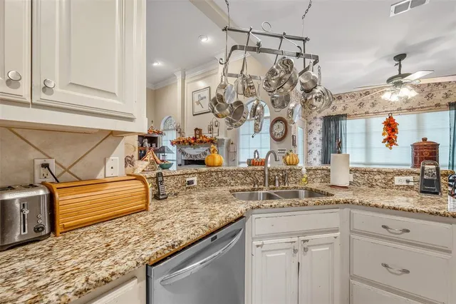 a kitchen with granite countertop a sink and a white wooden cabinets