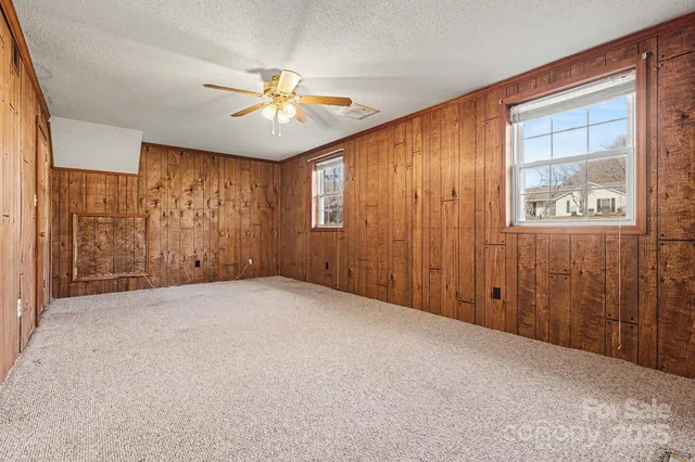 an empty room with windows and fan