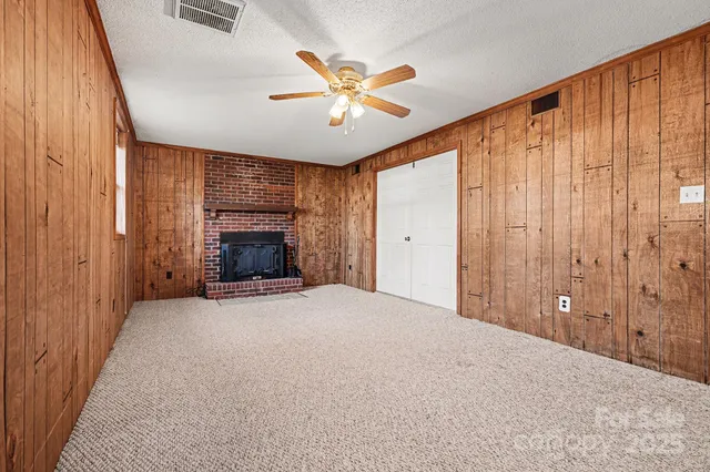 an empty room with ceiling fan and windows