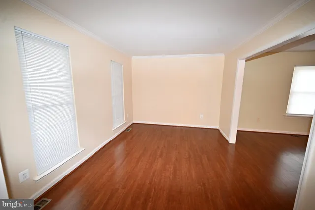 an empty room with wooden floor fireplace and windows