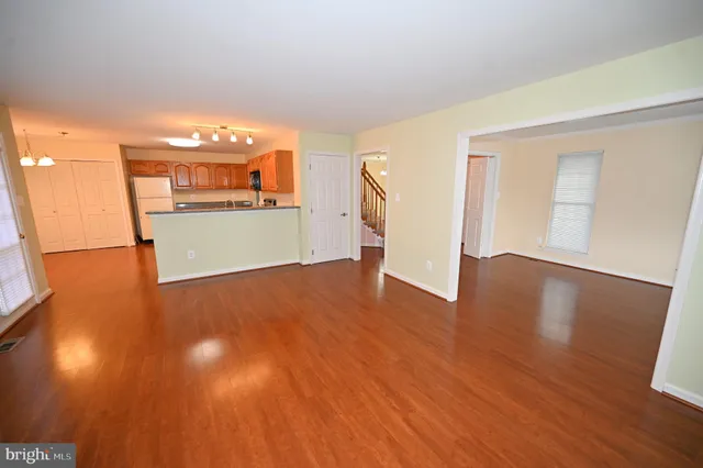 a kitchen with stainless steel appliances a refrigerator a stove a sink a microwave a refrigerator white cabinets and wooden floor