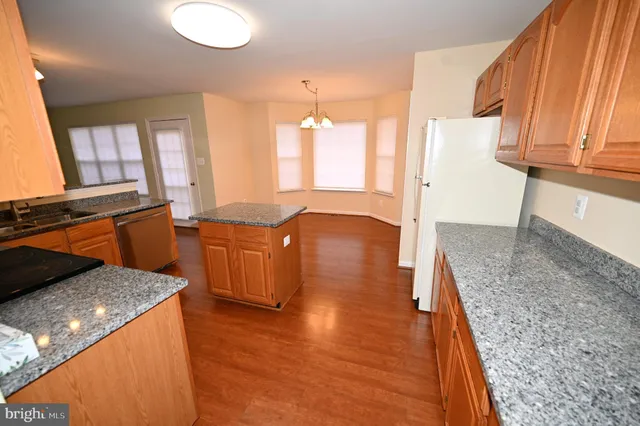 a large kitchen with stainless steel appliances granite countertop a refrigerator a stove top oven a sink and dishwasher