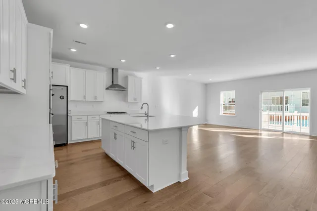 a large kitchen with stainless steel appliances granite countertop a large counter top a sink and a refrigerator