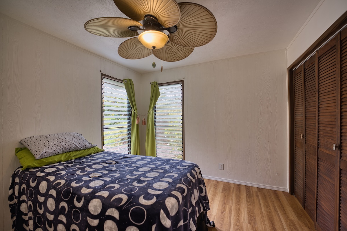 173 Opio Road Hilo, HI 96720 - Photo 18 of 27 a bedroom with a bed and a chandelier