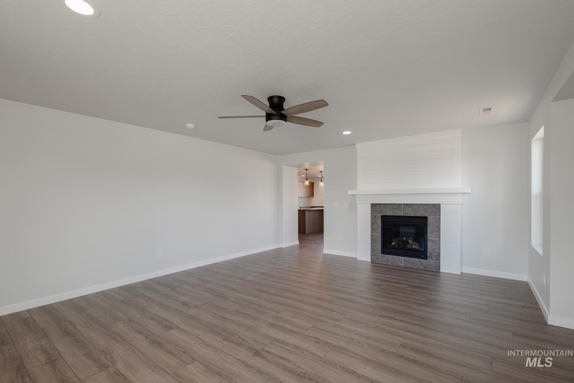 3270 West Morere Drive Meridian, ID 83642 - Photo 11 of 26 Unfurnished living room featuring a tiled fireplace, wood finished floors, recessed lighting, and ceiling fan