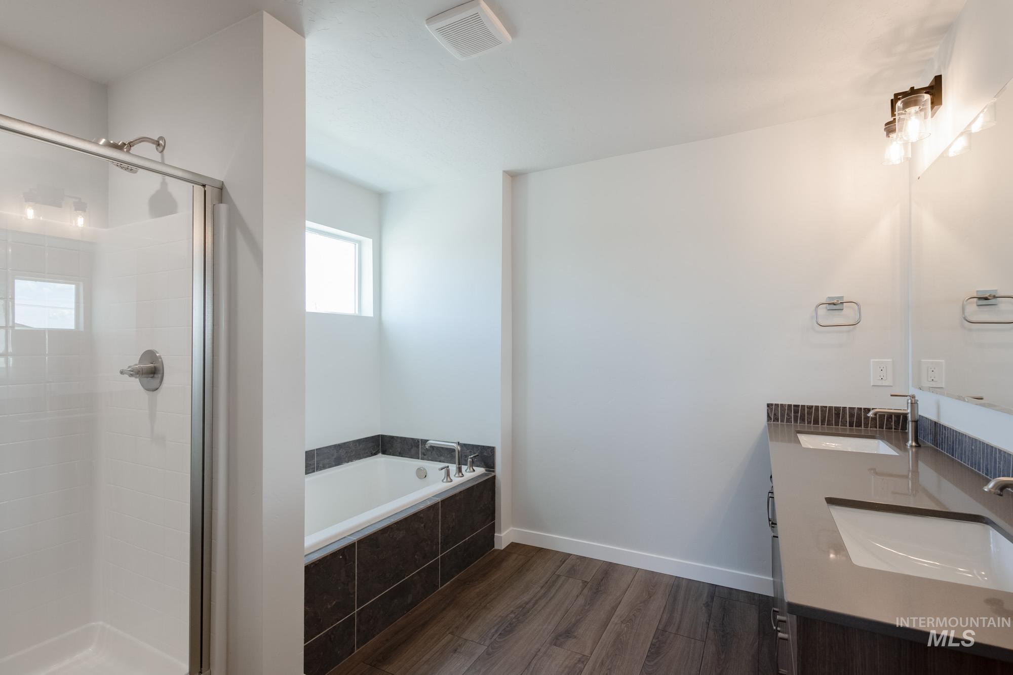 3270 West Morere Drive Meridian, ID 83642 - Photo 18 of 26 Bathroom with dark wood-type flooring, double vanity, a stall shower, and a bath