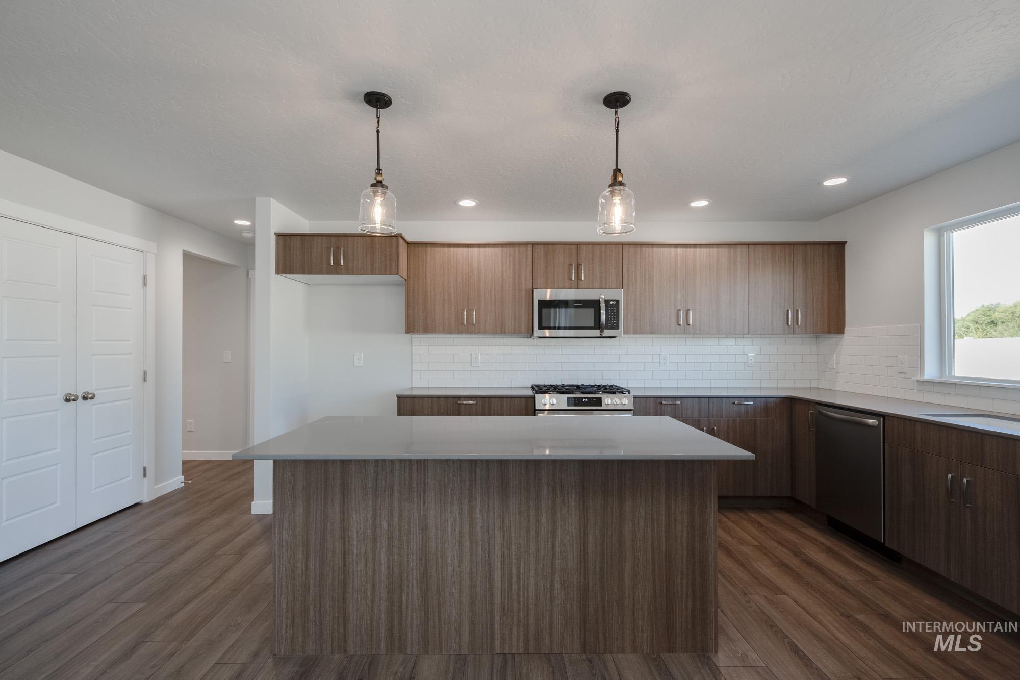 3270 West Morere Drive Meridian, ID 83642 - Photo 4 of 26 Kitchen featuring hanging light fixtures, dark wood-style flooring, tasteful backsplash, stainless steel appliances, and recessed lighting
