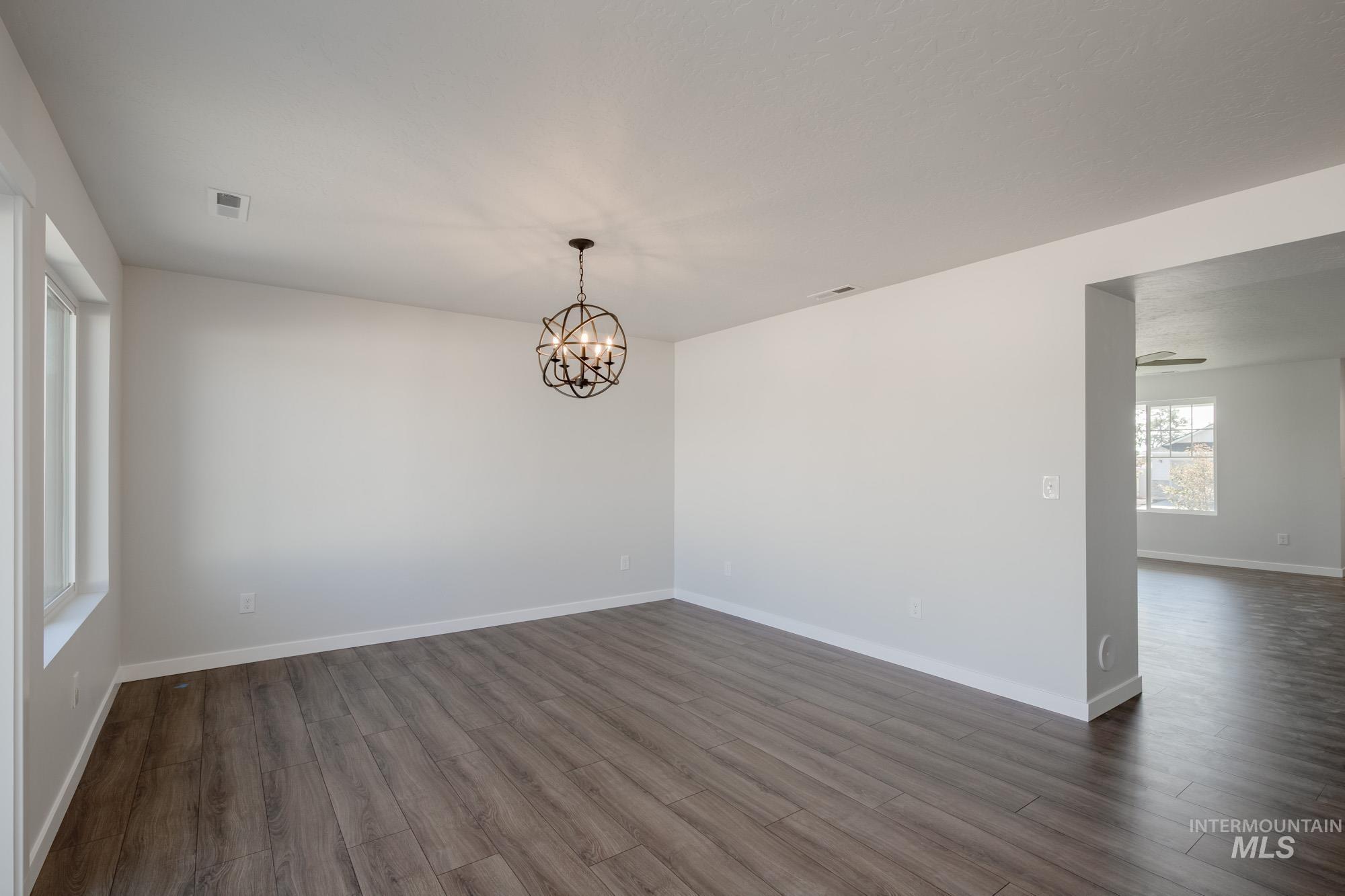 3270 West Morere Drive Meridian, ID 83642 - Photo 6 of 26 Spare room with dark wood-style floors and a chandelier