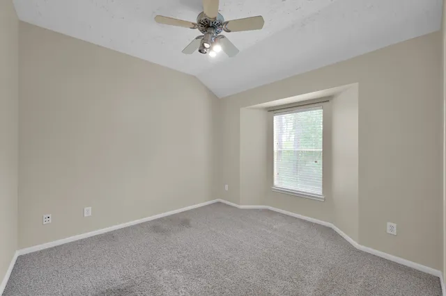a view of an empty room and chandelier fan