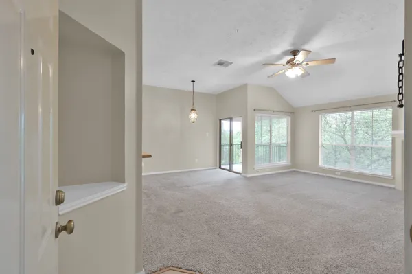 a view of an empty room with chandelier fan and fire place