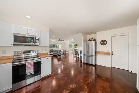 a kitchen with stainless steel appliances a stove a refrigerator a stove a oven with white cabinets and wooden floor