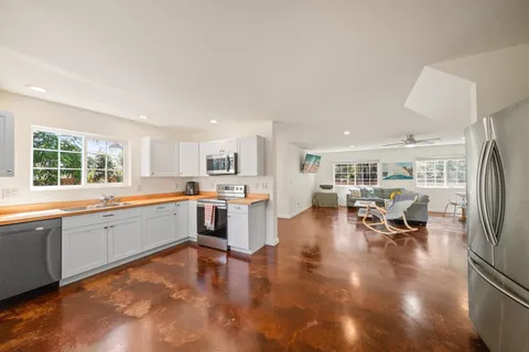 a large white kitchen with lots of counter top space and stainless steel appliances