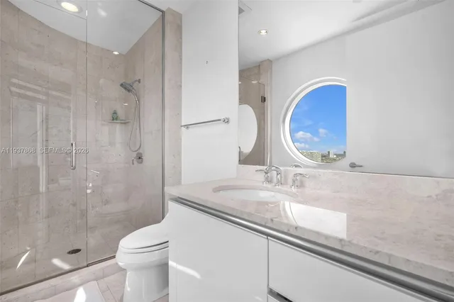 a bathroom with a granite countertop sink a toilet and shower
