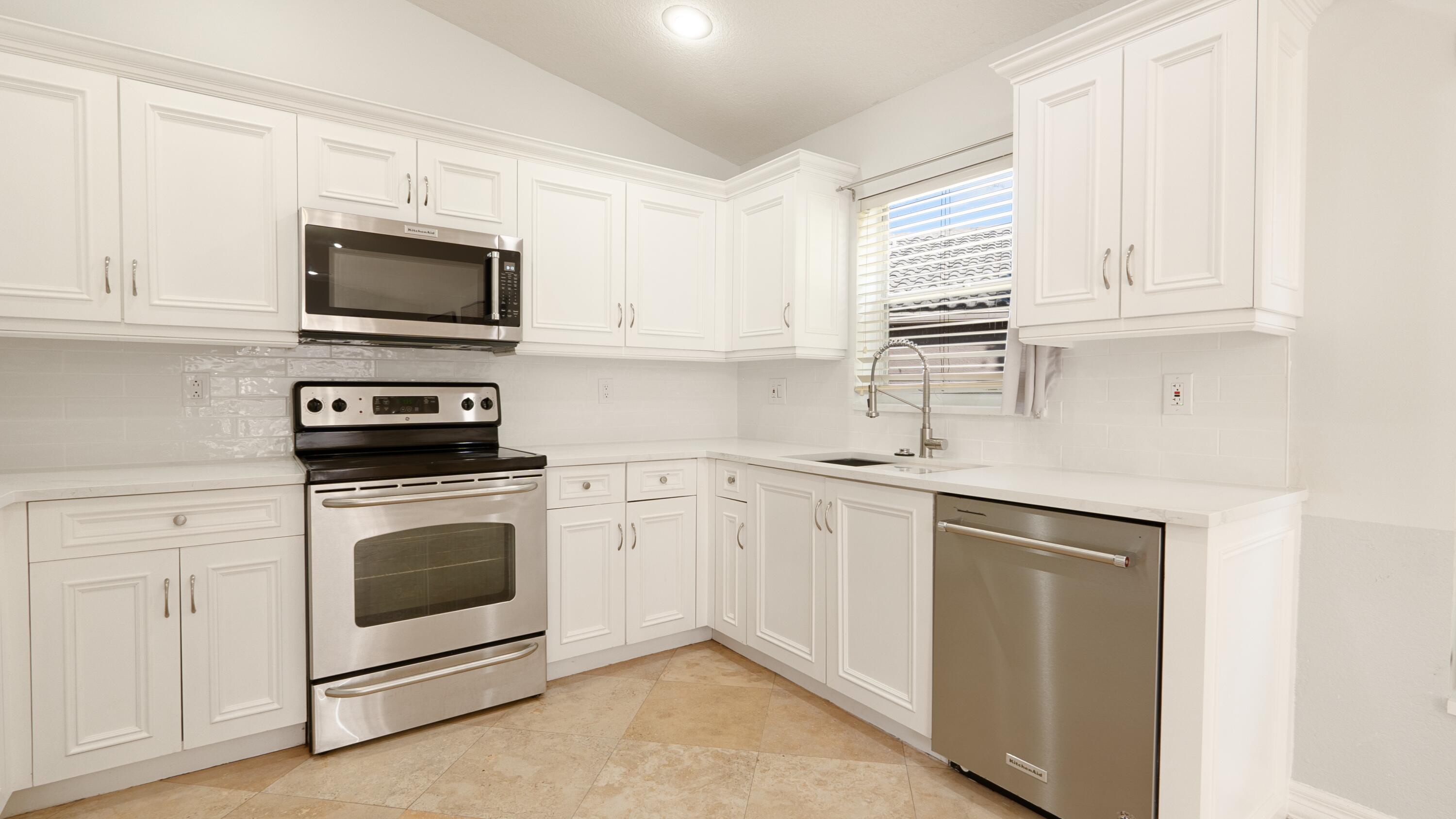 10789 Barque Court Boca Raton, FL 33498 - Photo 9 of 31 a kitchen with white cabinets stainless steel appliances and sink