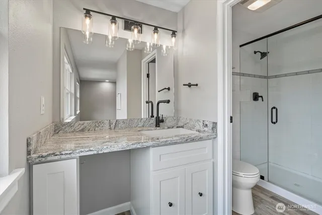 a bathroom with a granite countertop sink toilet and shower