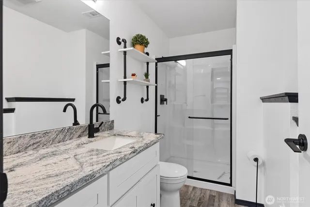 a bathroom with a granite countertop sink mirror toilet and shower