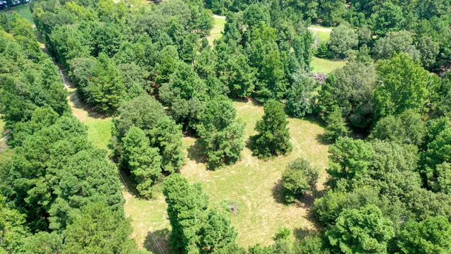 an aerial view of residential houses with outdoor space and trees all around