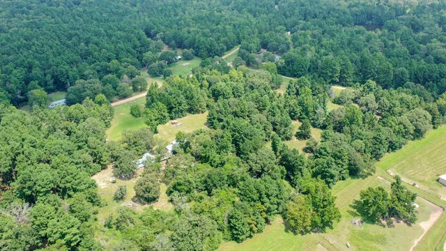 an aerial view of residential house with outdoor space and trees all around