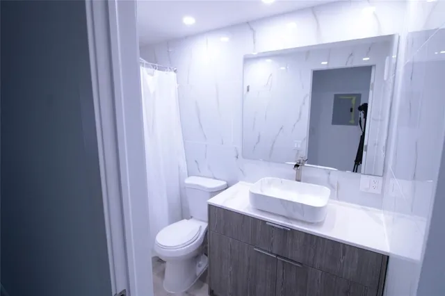 a bathroom with a sink a toilet a mirror and shower