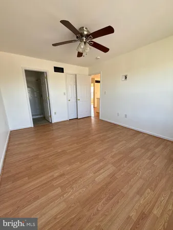 an empty room with wooden floor ceiling fan and windows