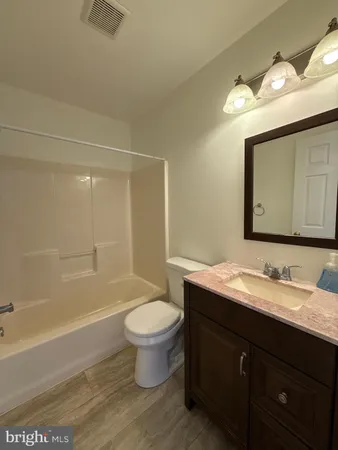 a bathroom with a bathtub sink vanity mirror and toilet