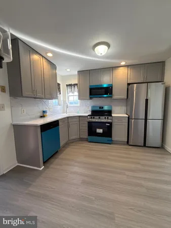 a large kitchen with stainless steel appliances granite countertop a stove refrigerator and a sink