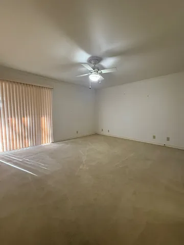 an empty room with a ceiling fan and window