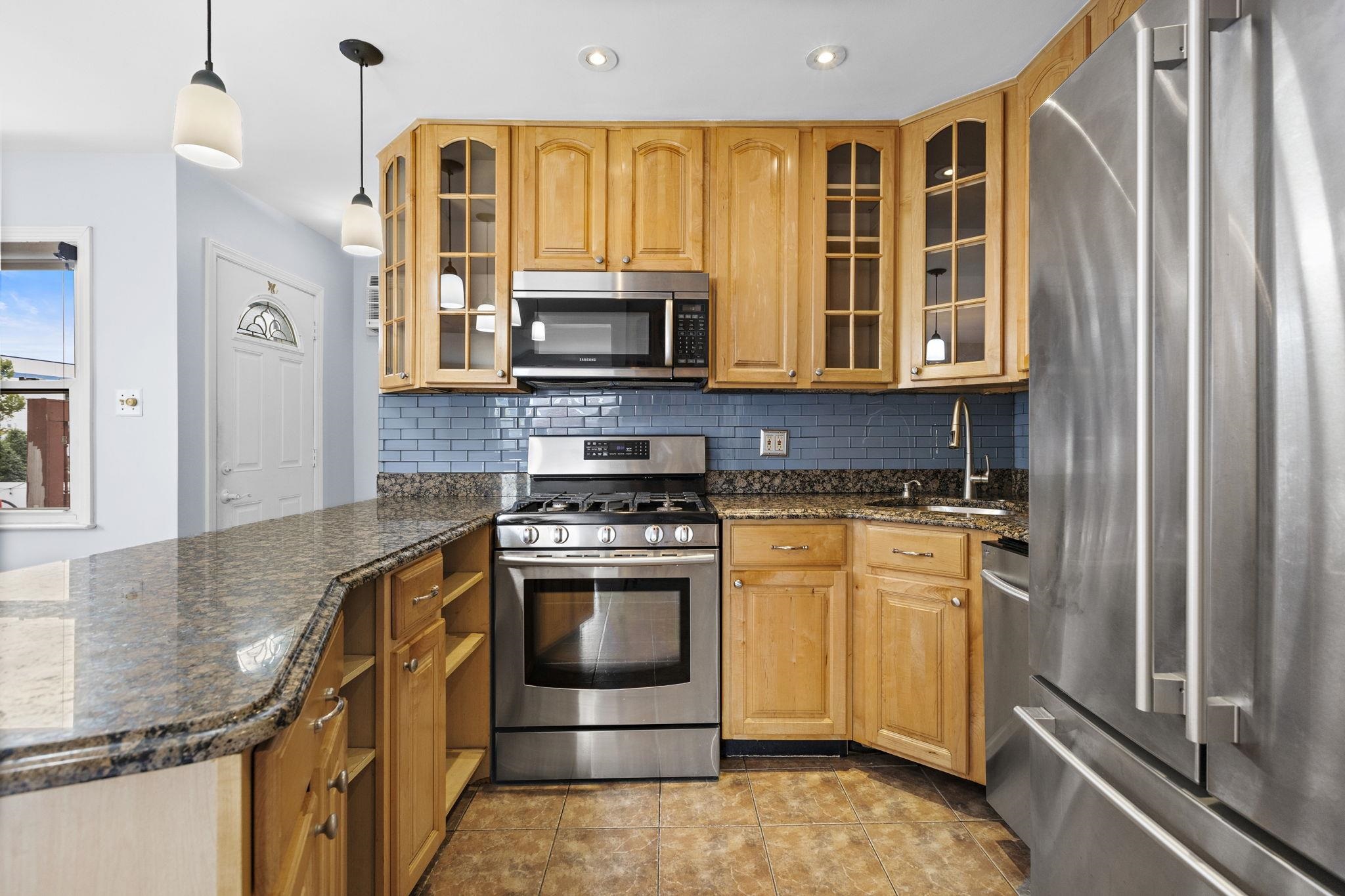 665 9th Street, Unit A Secaucus, NJ 07094 - Photo 6 of 17 a kitchen with stainless steel appliances granite countertop a stove a microwave and a refrigerator