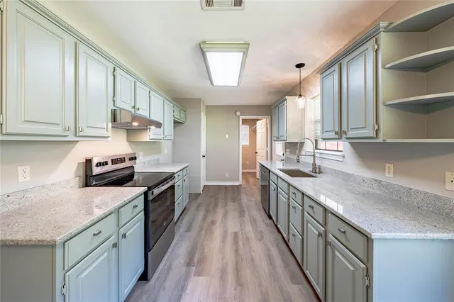 a kitchen with granite countertop a sink a counter top space stainless steel appliances and cabinets