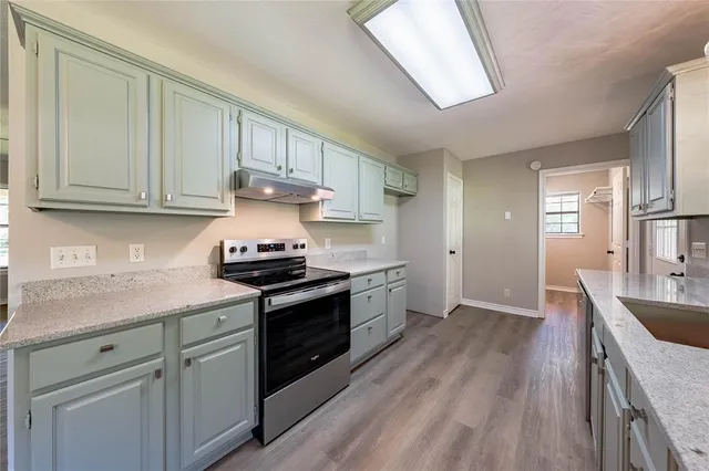 a kitchen with granite countertop wooden cabinets and a stove