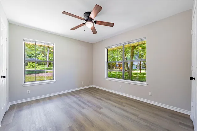 a view of a big room with wooden floor a ceiling fan and windows