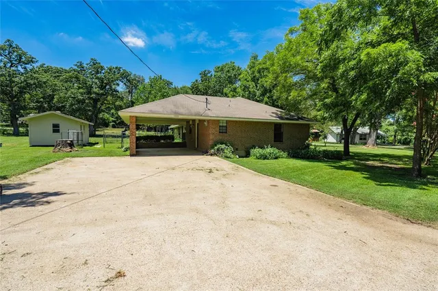 a view of a house with a yard and large tree