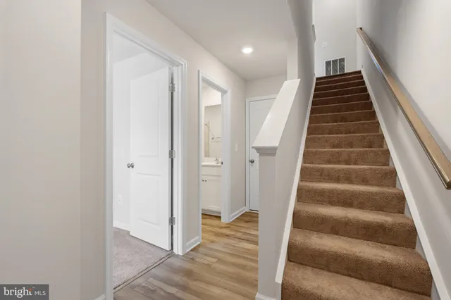 a view of staircase with wooden floor and white walls