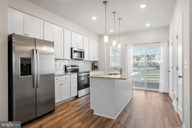 a kitchen with stainless steel appliances a refrigerator a sink cabinets and wooden floor