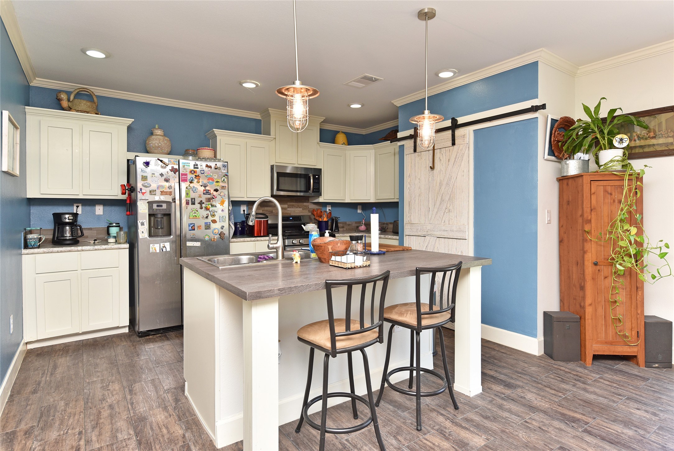 3221 Pecha Lane Rosenberg, TX 77471 - Photo 7 of 46 a kitchen with stainless steel appliances kitchen island granite countertop a refrigerator a microwave a stove and a dining table with wooden floor